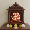 Om 3D printed wall decor placed inside a home temple with marigold flowers